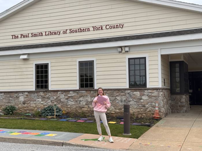 Brooke Shupp holding Pages of Purple materials outside The Paul Smith Library of Southern York County.