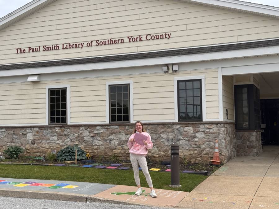 Brooke Shupp holding Pages of Purple materials outside The Paul Smith Library of Southern York County.